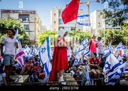 Tel Aviv, Israël. 18 juillet 2023. Un manifestant déguisé en personnage de « The Handmaid's Tale » tient un drapeau lors d'une manifestation à tel Aviv. Mardi, des dizaines de milliers de manifestants ont bloqué les autoroutes et les gares et ont défilé dans le centre de tel Aviv au cours d'une journée de manifestations à l'échelle du pays contre le plan litigieux de réforme judiciaire du Premier ministre Benjamin Netanyahu. Crédit : SOPA Images Limited/Alamy Live News Banque D'Images