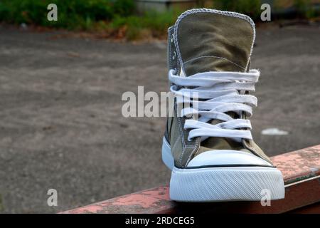 Trendsetter, baskets rétro dans un design culte à la mode avec un capuchon en caoutchouc blanc se tiennent sur une poutre en acier rouge. Vue avant. Banque D'Images