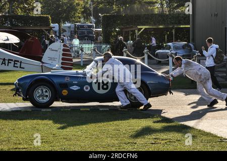Mécaniciens poussant une voiture de course classique AC Cobra 289 à courir tôt le matin au Goodwood Revival 2013. Préparation de l'événement Banque D'Images