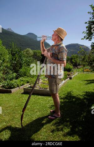 Briançon, France. 20 juillet 2023. Un homme de 73 ans travaille dans son potager. Il boit de l'eau dans une bouteille pour rester hydraté, France le 20 juillet 2023. Ilustration de l'importance de l'hydratation chez le sujet âgé en période de forte chaleur ou de vagues de chaleur. Photo de Thibaut Durand/ABACAPRESS.COM crédit : Abaca Press/Alamy Live News Banque D'Images