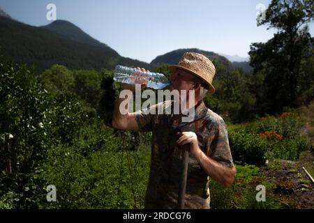 Briançon, France. 20 juillet 2023. Un homme de 73 ans travaille dans son potager. Il boit de l'eau dans une bouteille pour rester hydraté, France le 20 juillet 2023. Ilustration de l'importance de l'hydratation chez le sujet âgé en période de forte chaleur ou de vagues de chaleur. Photo de Thibaut Durand/ABACAPRESS.COM crédit : Abaca Press/Alamy Live News Banque D'Images