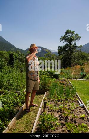 Briançon, France. 20 juillet 2023. Un homme de 73 ans travaille dans son potager. Il boit de l'eau dans une bouteille pour rester hydraté, France le 20 juillet 2023. Ilustration de l'importance de l'hydratation chez le sujet âgé en période de forte chaleur ou de vagues de chaleur. Photo de Thibaut Durand/ABACAPRESS.COM crédit : Abaca Press/Alamy Live News Banque D'Images