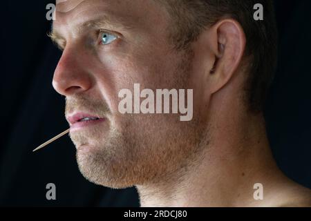 gros plan abstrait de cure-dent dans un fond noir de bouche d'homme Banque D'Images