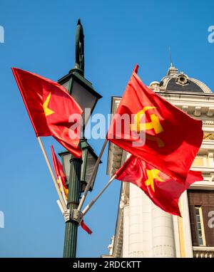 Le marteau et la faucille communistes et les drapeaux vietnamiens étoilés d'or volent d'un lampadaire à l'extérieur de l'Opéra de Hanoi, à Hanoi, Vietnam Banque D'Images