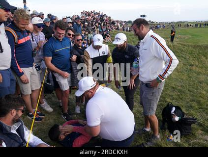 L'Espagnol Jon Rahm marche au-dessus d'un fan qui a été frappé par un tir de tee-shirt décalé pendant la première journée de l'Open au Royal Liverpool, Wirral. Date de la photo : jeudi 20 juillet 2023. Banque D'Images