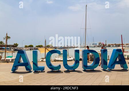 Panneau avec de grandes lettres bleues lisant Alcudia, sur la promenade de la station balnéaire de Alcúdia, dans le nord de l'île méditerranéenne de Majorque en Espagne. Banque D'Images