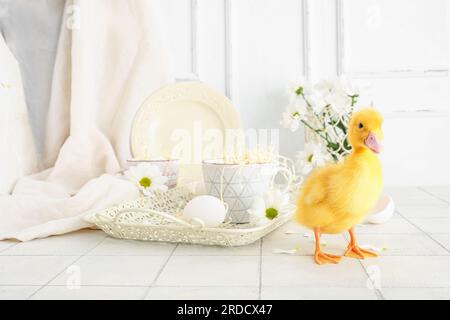 Mignon caneton, plateau avec des tasses et des fleurs de camomille sur la table carrelée blanche Banque D'Images