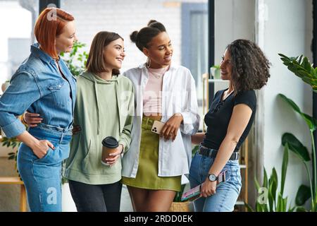 femmes multiethniques joyeuses et élégantes dans des vêtements décontractés élégants se regardant dans une atmosphère amicale de club d'intérêt des femmes, soutien mutuel, donc Banque D'Images
