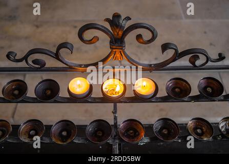 Un support de bougie en métal décoré dans une église et trois bougies allumées Banque D'Images