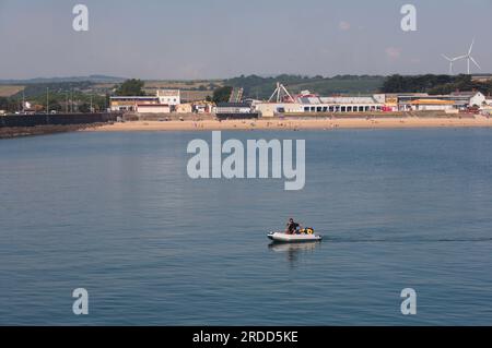 Sandy Bay Porthcwal avec divertissements de Coney Beach et homme en canot dans l'après-midi calme et chaud de juin Banque D'Images