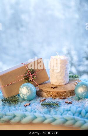 Fond des produits de Noël. Bougie de motif boule de neige blanche brûlant, cadeau de Noël enveloppé dans du papier brun avec ficelle blanche et rouge. Banque D'Images