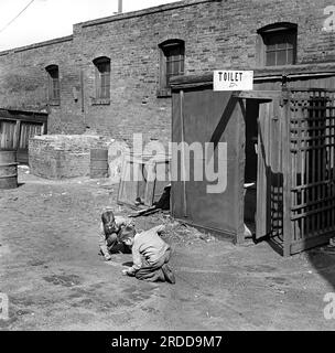 Deux enfants jouant aux billes devant les toilettes publiques, St. Louis, Missouri, États-Unis, Arthur Rothstein, États-Unis Farm Security Administration, mars 1936 Banque D'Images