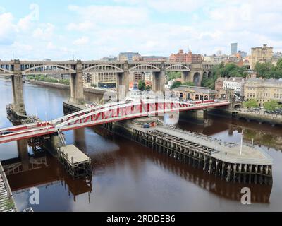 Newcastle, Royaume-Uni - 20 juillet 2023 : le pont tournant rouge sur la rivière Tyne. Pont routier et ferroviaire de haut niveau en arrière-plan. Banque D'Images