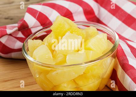Un gros plan de délicieux morceaux d'ananas dans le sirop juteux sur un fond en bois avec espace de copie Banque D'Images
