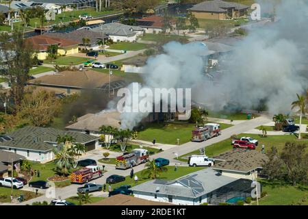Vue du dessus de la maison privée en feu sur le feu et les pompiers éteignant les flammes après un court-circuit causé pour enflammer le toit endommagé par un ouragan Banque D'Images