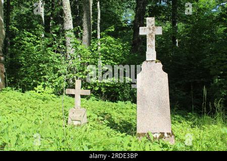 Deux pierres tombales grises avec des croix sur le dessus dans un cimetière à Eglaine, Lettonie Banque D'Images