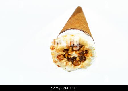 Cône de vanille de crème glacée avec garniture de morceaux de pépites de chocolat, noix et caramel dans une galette croustillante cônes, foyer sélectif de la fonte de la crème glacée froide twi Banque D'Images