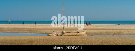 Côte de Morondava avec un bateau en bois baobab à marée basse sur sable, fond avec panorama des gens Banque D'Images