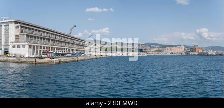 TRIESTE, ITALIE - mai 29 2023 : paysage urbain avec des bâtiments portuaires et une myriade de truks et d'autocars bordés sur le quai, tourné de la mer en lumière vive le 29 mai, Banque D'Images