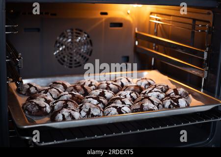 Biscuits aux pépites de chocolat frais saupoudrés de sucre en poudre cuits au four. Délicieuse cuisson maison, dessert sucré sur des plateaux en papier au four. Banque D'Images