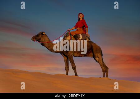 Un magnifique modèle fait une promenade à dos de chameau à travers le désert saharien au Maroc Banque D'Images