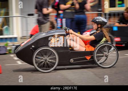 Ringwood, Hampshire, Royaume-Uni, 16 juillet 2023. Le Grand Prix britannique des voitures à pédales. Pilote dans un véhicule à pédales motorisé par l'homme ou une femme qui court dans les rues. Banque D'Images