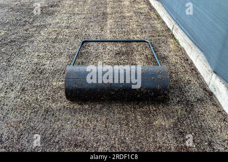 Rouler les graines d'herbe fraîchement semées avec un rouleau métallique rempli d'eau. Banque D'Images