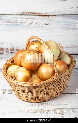 Oignon cru frais dans un panier sur fond de bois. Concept de saison de récolte des oignons. Légumes pour une alimentation saine Banque D'Images