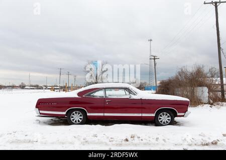 Une voiture rouge d'époque se trouve sur un paysage Americana couvert de neige Banque D'Images