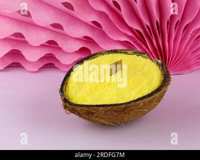 Bougies en vrac jaunes en noix de coco avec une mèche en bois sur le fond rose. Fabrication de bougies à la maison à partir d'huile de palme. Production de bougies en vrac à la main. Banque D'Images