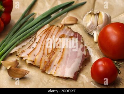 Bacon fumé cru, tranches de poitrine striées, tranches de bacon frais et fines. Morceaux de saindoux frais ou salo et bacon roulés avec des cornichons. Délicatesse de viande, bouillie p Banque D'Images