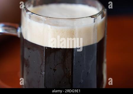 Bière brune dans une tasse à bière. Bière tchèque sur la table du bar restaurant pub à Prague, République tchèque. Banque D'Images