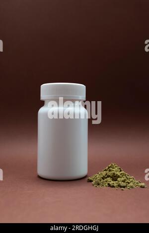 Pilules de cannabis en bouteille blanche, récipient avec poudre de protéine de chanvre à côté sur fond brun. Médecine alternative, médicaments à base de plantes. Copier l'espace pour Banque D'Images