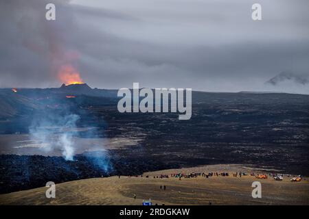 Fagradalsfjall, Islande. 21 juillet 2023. La lave entre en éruption dans le cratère d’un volcan près de la montagne Litli-Hrútur, à environ 40 kilomètres au sud-ouest de Reykjavik. Au premier plan, les « touristes volcaniques » regardent les flammes. L’Islande a connu une éruption volcanique pour la troisième année consécutive. Crédit : Philipp Schulze/dpa/Alamy Live News Banque D'Images