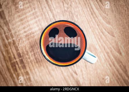 Tasse à café avec des cris drôles dans le visage de peur, vue de dessus. Ouvrez la bouche pleurante dans la tasse sur le fond de table. Choqué, stressé, en colère, effrayé et furieux foa Banque D'Images