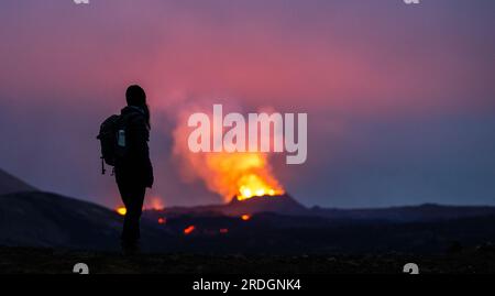 Fagradalsfjall, Islande. 21 juillet 2023. La lave entre en éruption dans le cratère d’un volcan près de la montagne Litli-Hrútur, à environ 40 kilomètres au sud-ouest de Reykjavik. Une jeune femme se tient au premier plan, regardant les flammes. L’Islande a connu une éruption volcanique pour la troisième année consécutive. Crédit : Philipp Schulze/dpa/Alamy Live News Banque D'Images