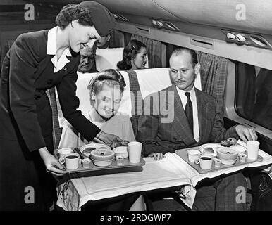 États-Unis : c. 1958 Une hôtesse de l'air sert un repas à un couple sur un vol d'American Airlines. Banque D'Images