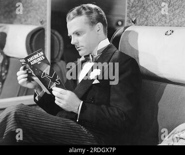 Hollywood, Californie : vers 1934 l'acteur James Cagney lit la brochure de sécurité à bord d'un avion d'American Airlines. Banque D'Images
