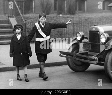 Washington, D.C. : c. 1928 Un écolier traversant le gusrd arrête la circulation pour laisser une jeune étudiante traverser la rue. Banque D'Images