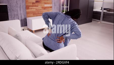 Femme souffrant de mal de dos ou de mal de dos dans le salon Banque D'Images