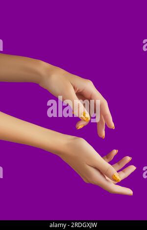 Des mains de femmes soignées avec un motif à ongles tendance sur fond violet Banque D'Images