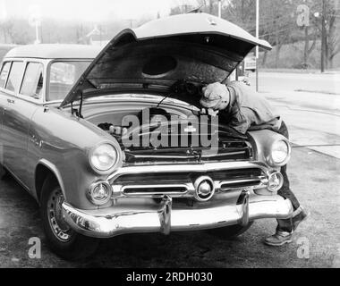 États-Unis : c. 1952 Un homme réparant son Ford Ranch Wagon de 1952 au bord de la route. Banque D'Images