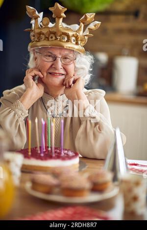 Une grand-mère chérie est assise à la table, son visage orné d'un sourire rayonnant qui reflète une vie d'amour et de sagesse. Devant elle, c'est l'anniversaire Banque D'Images