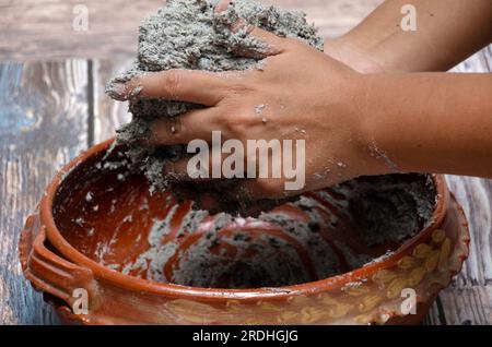 Mains de femme mélangeant de la pâte de maïs pour faire des tortillas. Cuisine mexicaine de base. Banque D'Images