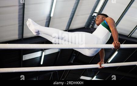 Force, fitness et gymnaste ou athlète masculin avec la pratique pour la compétition avec africain au gymnase. Gymnastique, sport et homme avec équilibre sur poutre pour Banque D'Images
