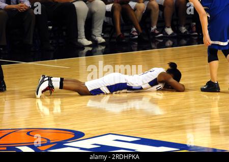 Joueur de basket-ball s'effondre avec chagrin après avoir perdu le tournoi de basket-ball de l'État. L'adversaire vérifie pour être sûr qu'elle est o.k. Le joueur pose la face à plat Banque D'Images