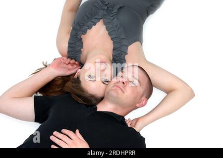 Beau couple se détendre en s'allongeant sur le sol proches les uns des autres. Les deux ne sourient pas et joue contre joue. Elle porte du gris et lui du noir. Banque D'Images