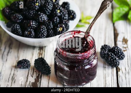Vue aérienne de conserves de mûres maison ou de confiture dans un pot Mason entouré de mûres biologiques fraîches. Mise au point sélective avec premier plan flou Banque D'Images