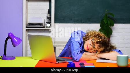 Enseignante fatiguée dans des lunettes dormant au bureau dans la salle de classe. Retour à l'école. Journée du savoir. Vacances scolaires. Étudiante universitaire surchargée de travail Banque D'Images