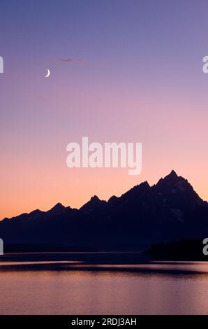 Jackson Lake, les montagnes Teton et un croissant de lune au coucher du soleil, Grand Teton National Park, Wyoming, USA Banque D'Images